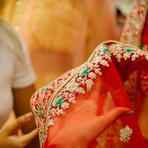Close-up of a beautifully embroidered red veil fabric being held, showcasing intricate craftsmanship and design.